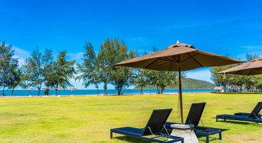 Large garden umbrella providing shade over an outdoor patio seating area in a landscaped garden.